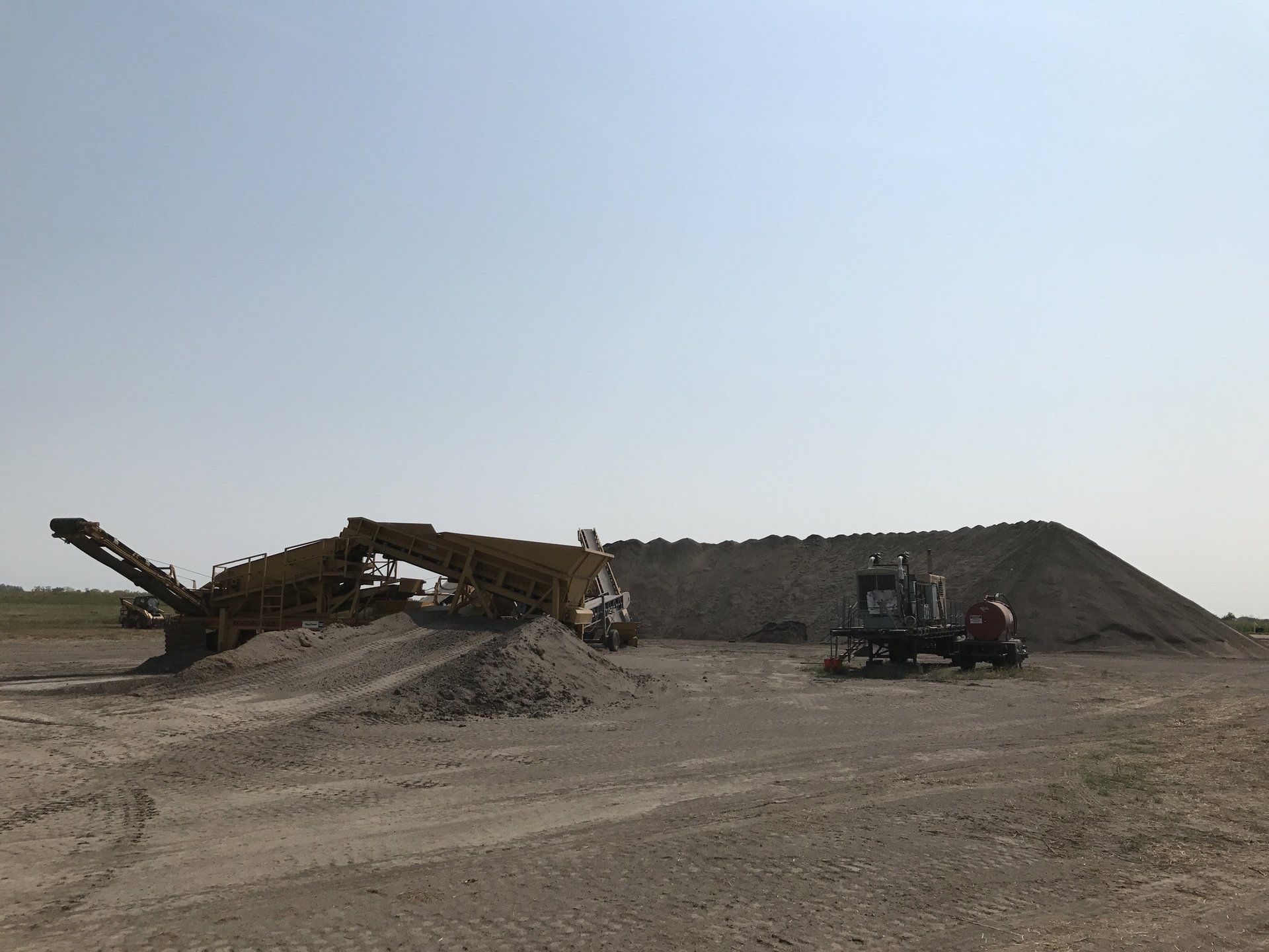 A large pile of dirt is sitting in the middle of a dirt field.