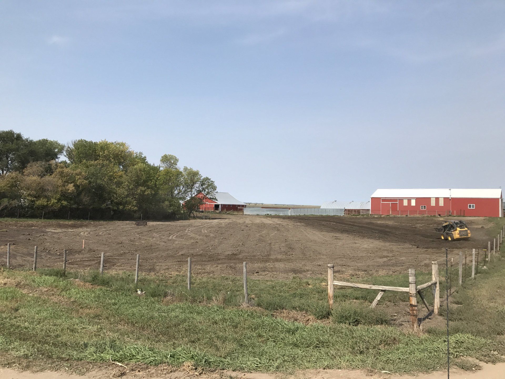 A fenced in field with a red barn in the background.