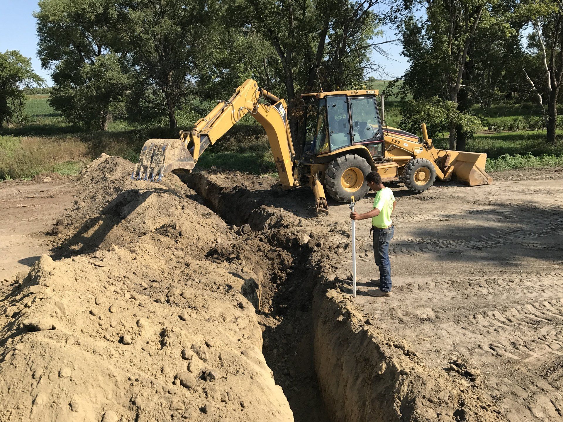 A man is standing in a trench next to a bulldozer.