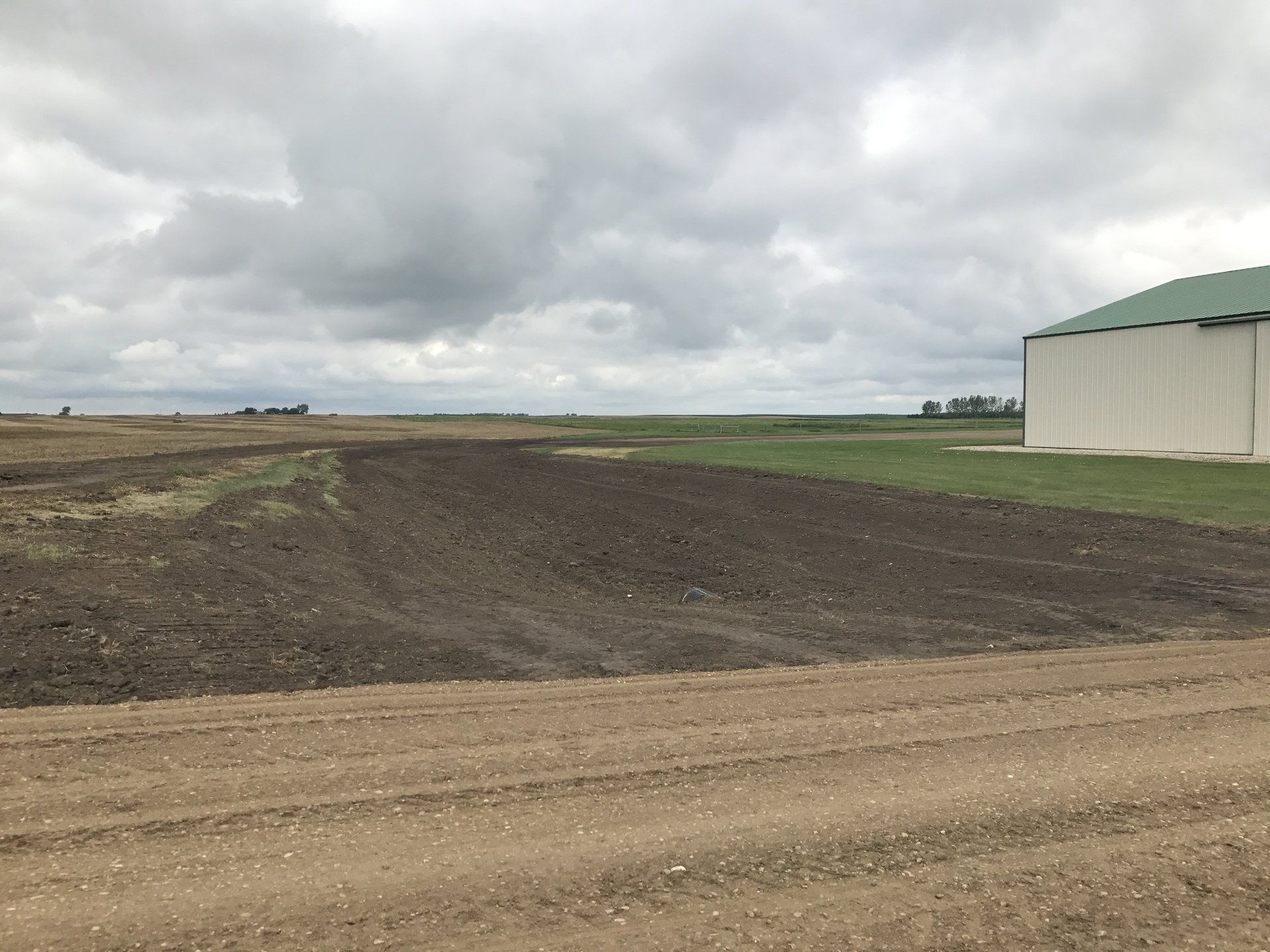 A large white building is sitting in the middle of a dirt field.