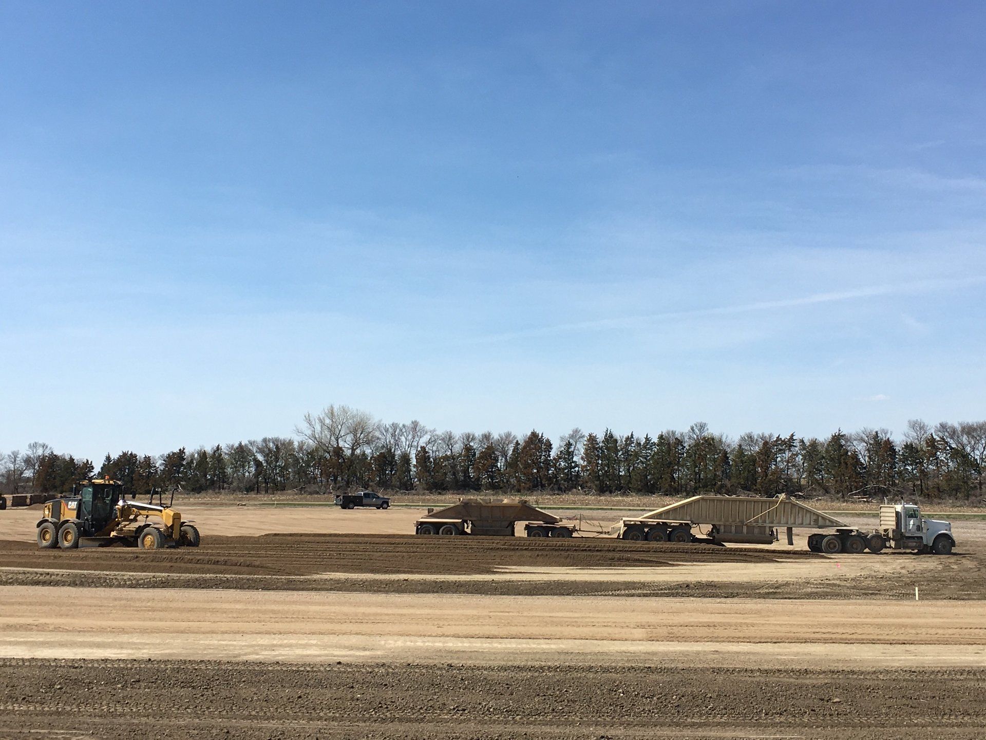 A large dirt field with tractors and trucks working on it.