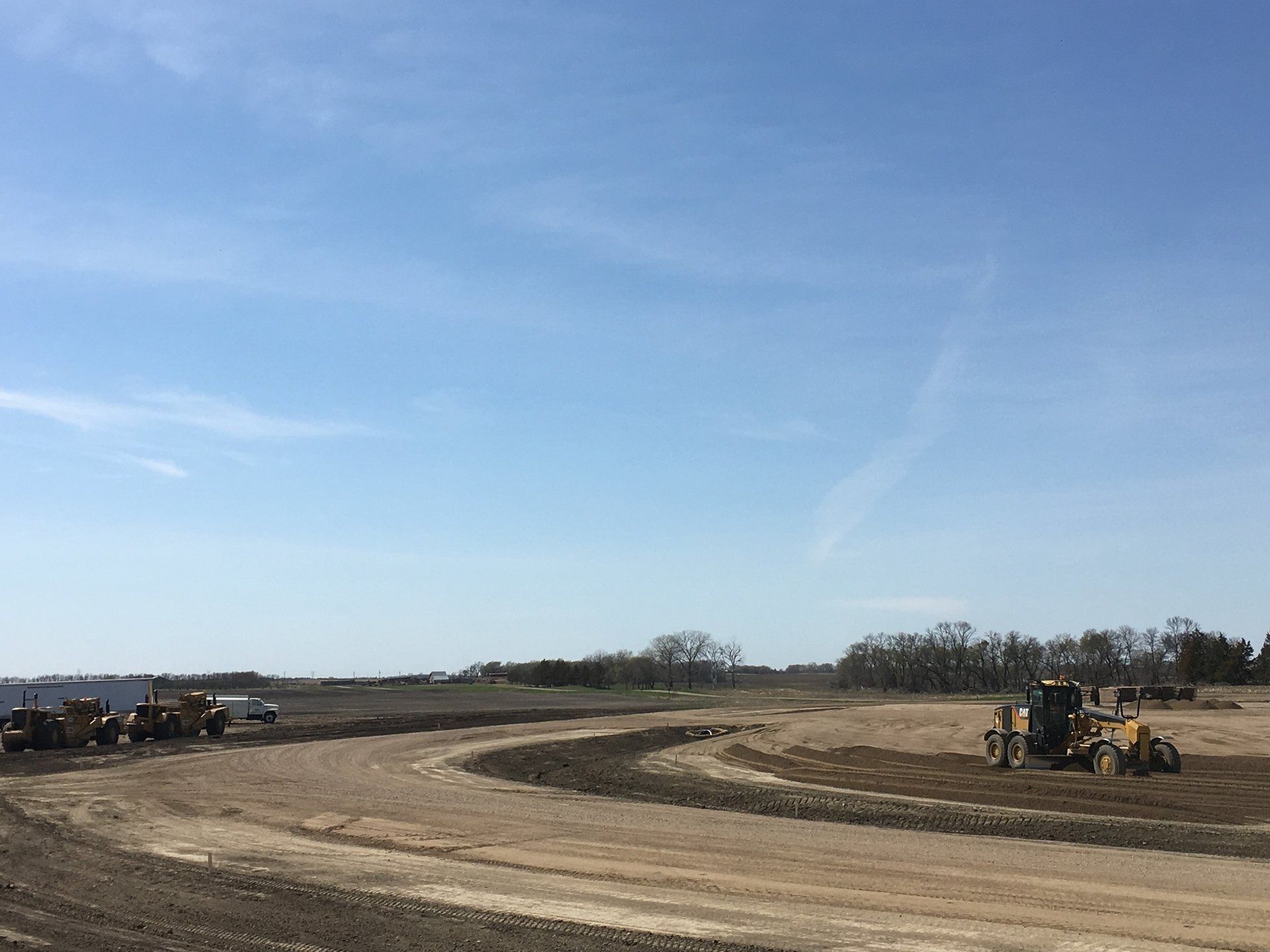 A group of construction vehicles are working on a dirt road.
