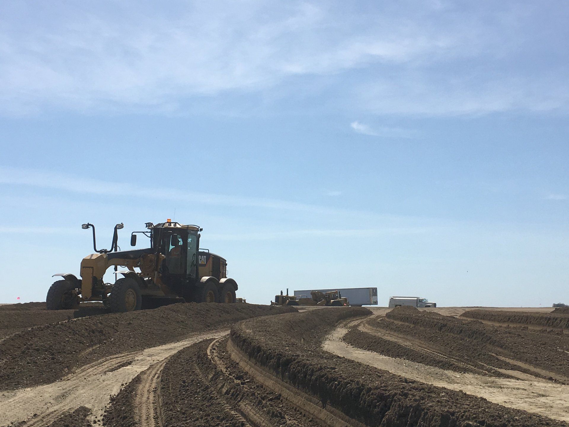 A bulldozer is driving down a dirt road in a field.