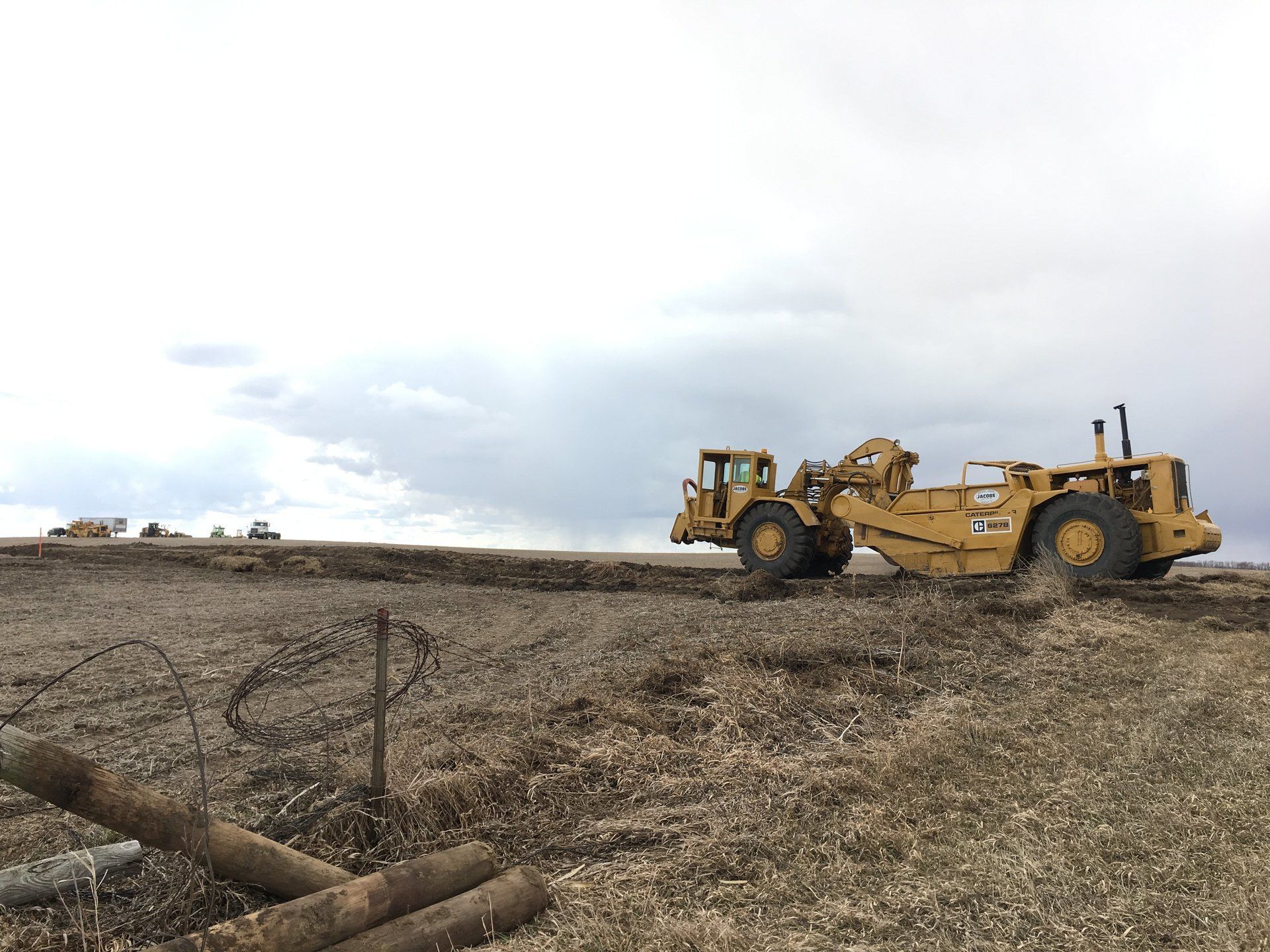 A bulldozer is driving down a dirt road in a field.