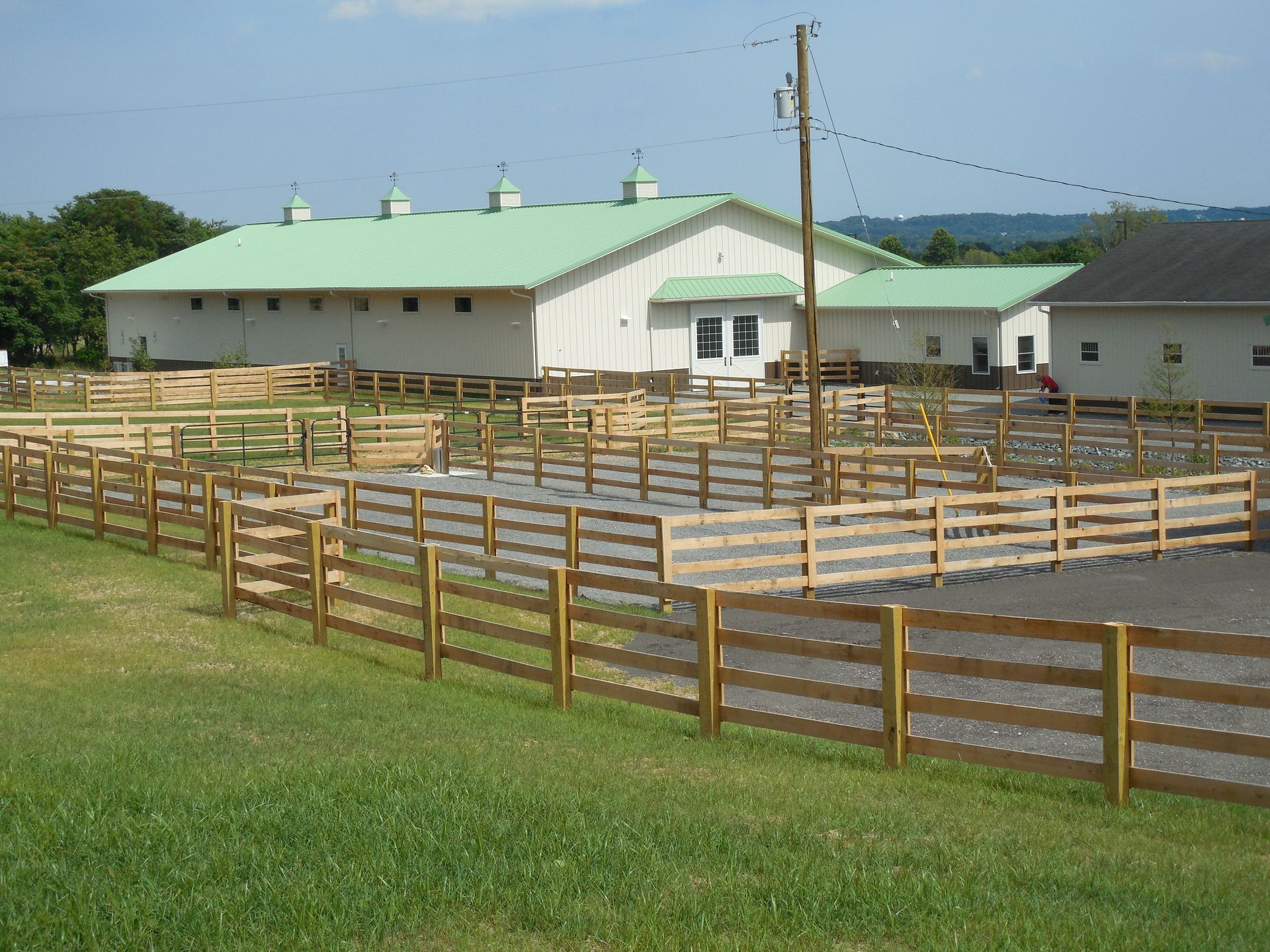 A large white building with a green roof is behind a wooden fence
