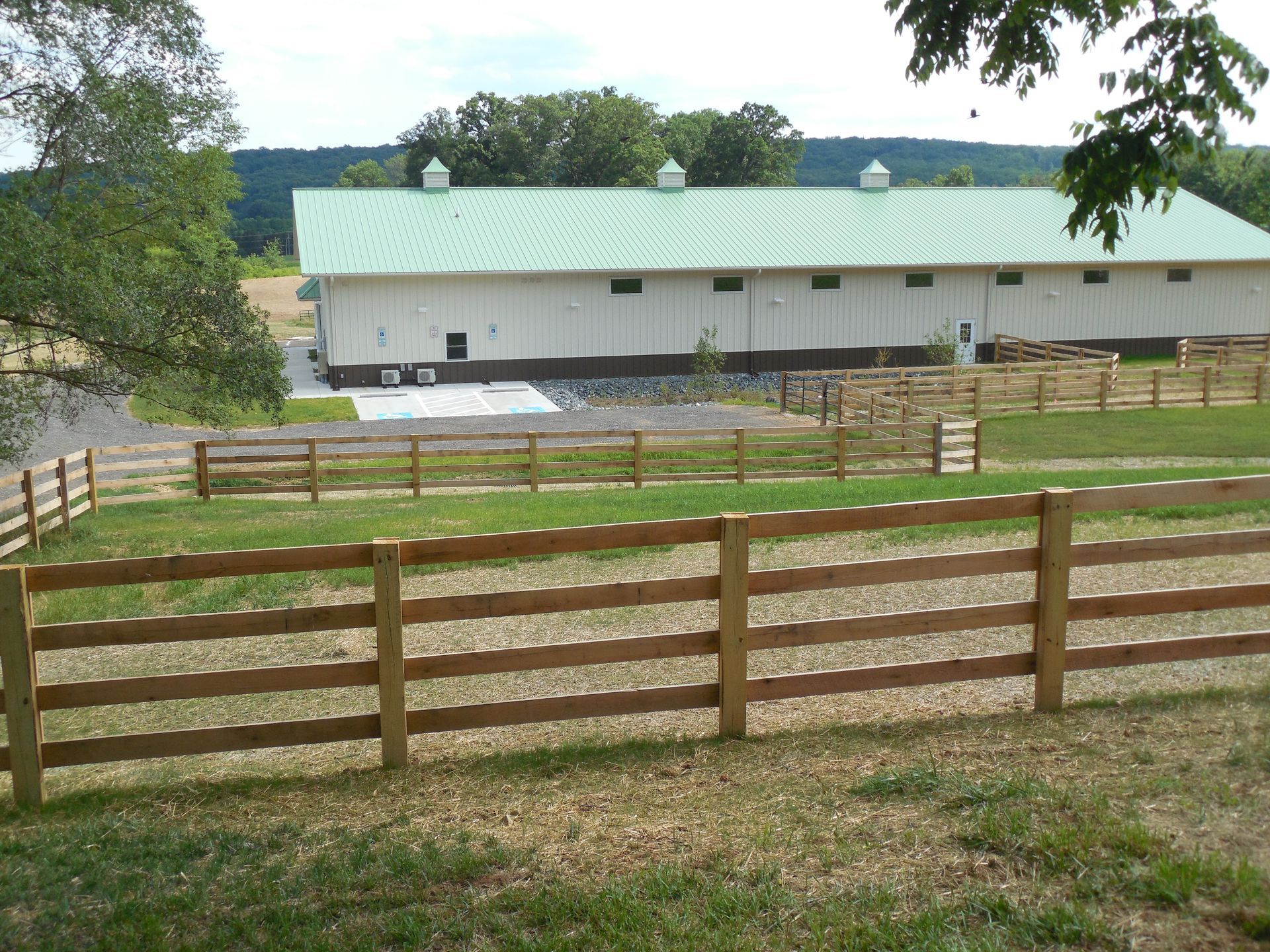 A large white building with a green roof is behind a wooden fence
