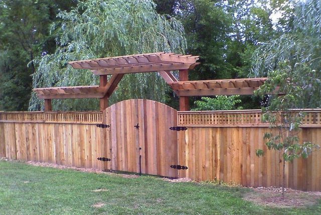 A wooden fence with a pergola and a gate