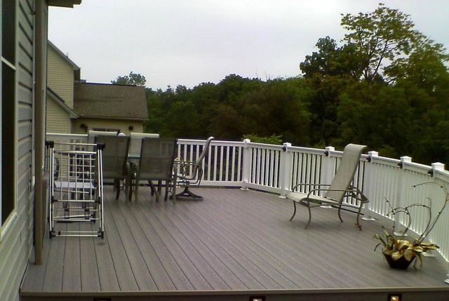 A deck with a white railing and chairs on it