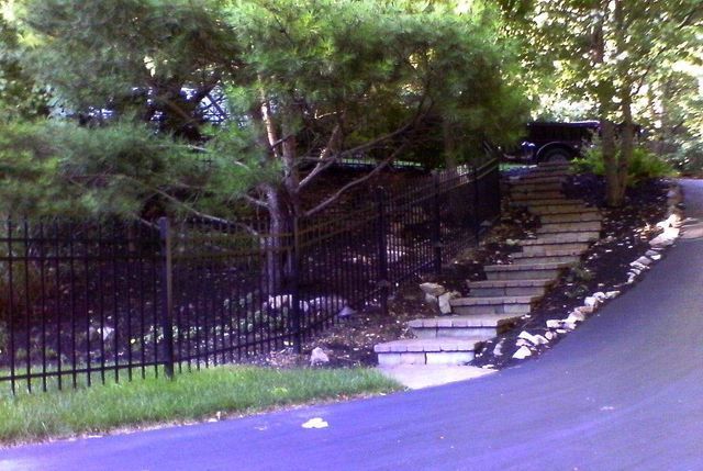 A black fence surrounds a staircase leading up to a house.