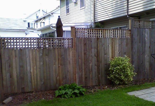 A wooden fence in a backyard with a house in the background