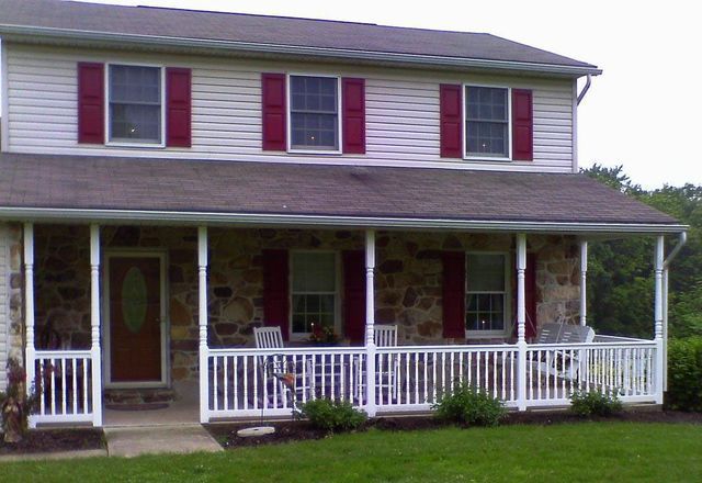 A white house with red shutters and a porch