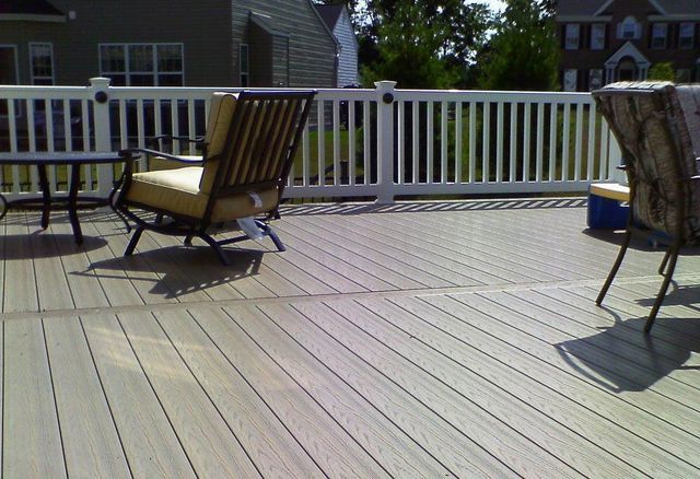 A deck with chairs and a table with a white railing