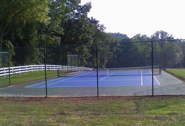 A tennis court with a fence around it and trees in the background