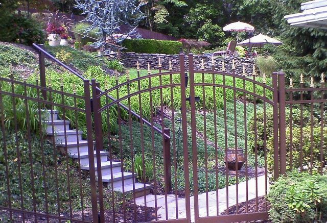 A metal fence surrounds a garden with stairs leading up to it