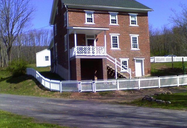A large brick house with a white picket fence around it