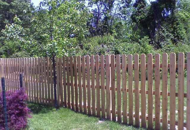 A wooden picket fence surrounds a lush green yard.