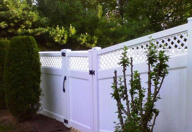 A white fence with a lattice design and a gate