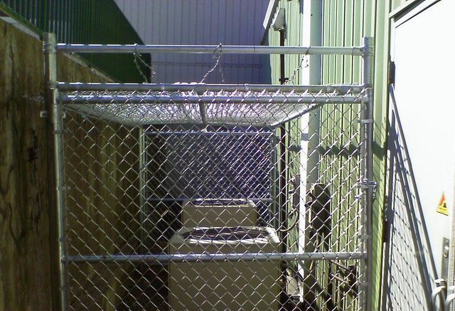 A chain link fence surrounds an alleyway between two buildings