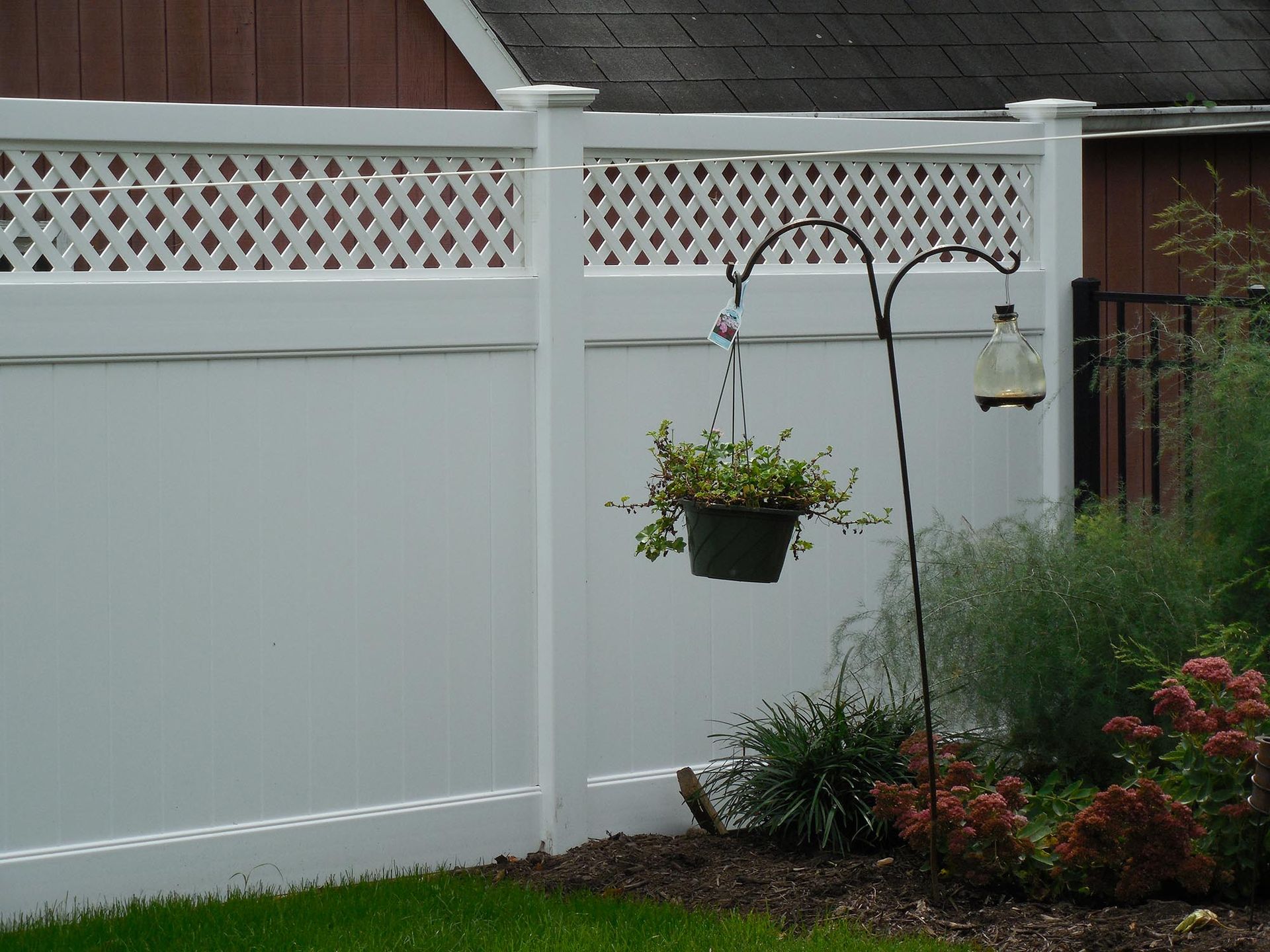 A white fence with a potted plant hanging from it