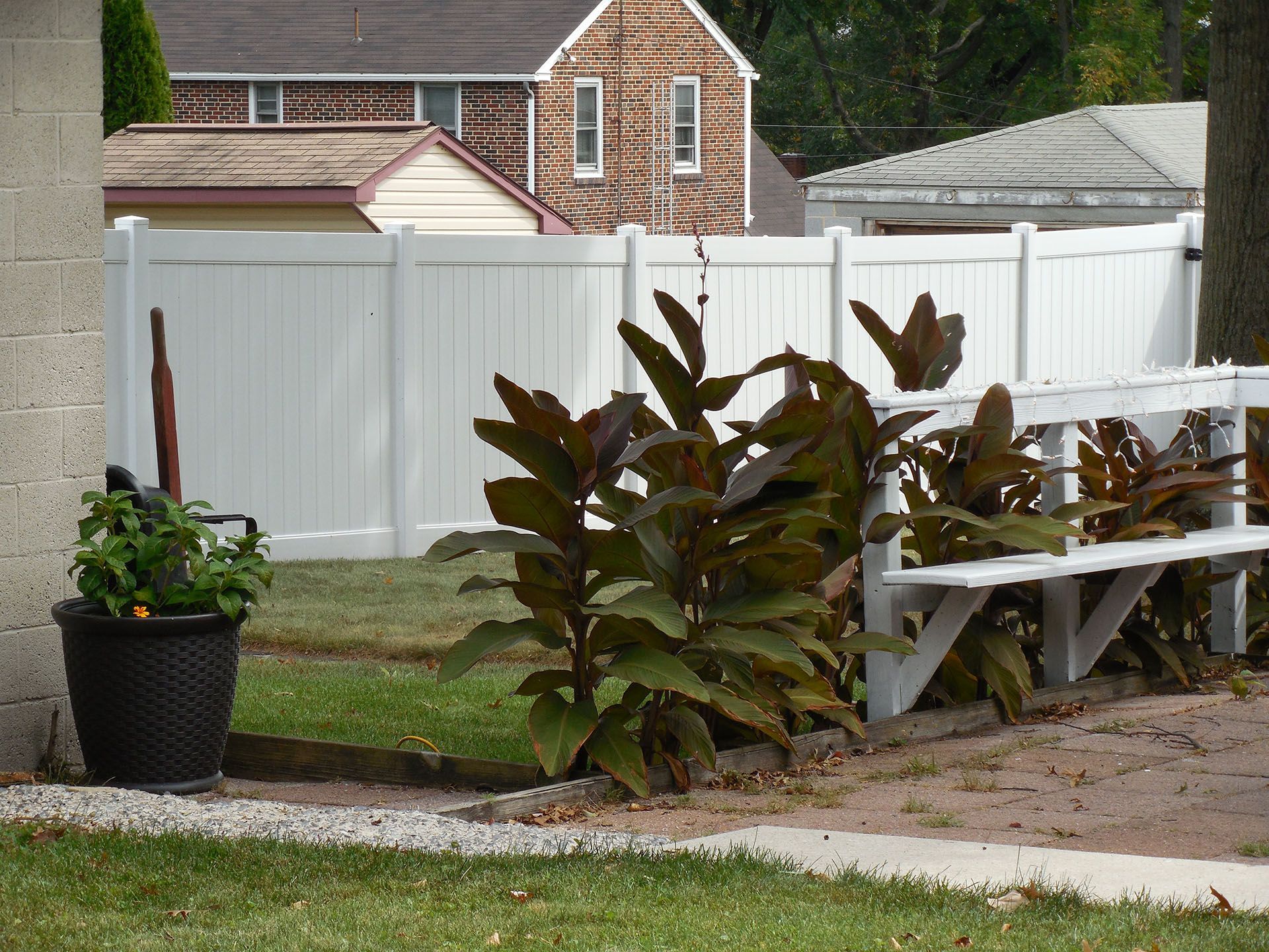 A white fence with a potted plant in front of it