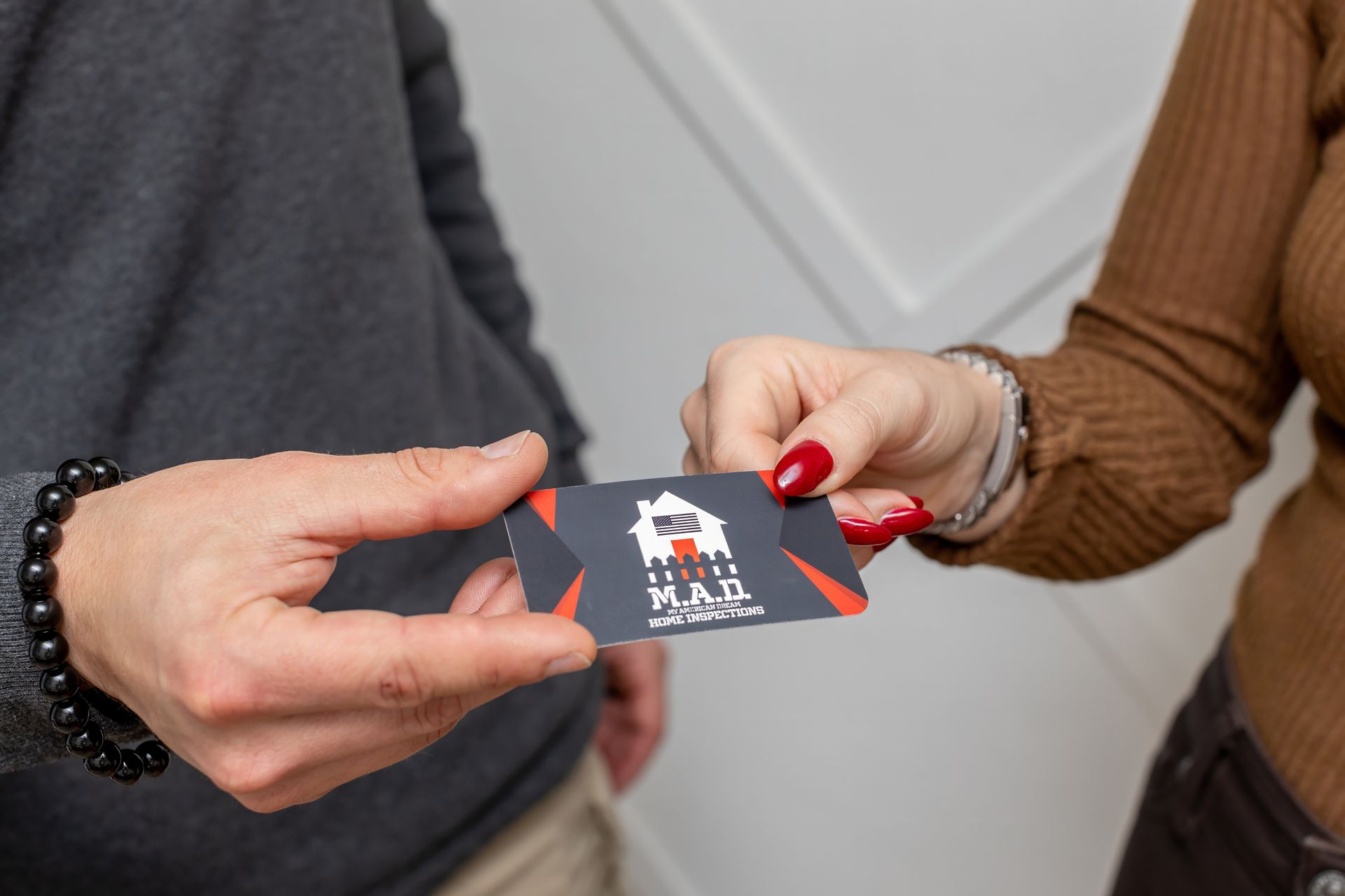 Person handing a business card to another. Card is black, red, and white.