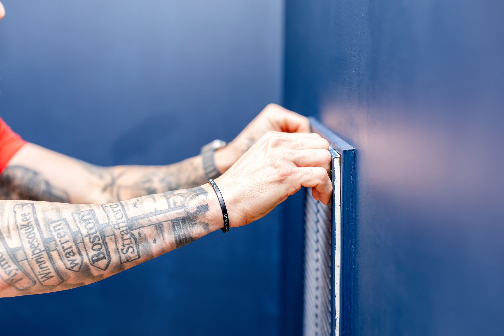 Person holding a metal ruler against a dark blue wall in an interior setting.