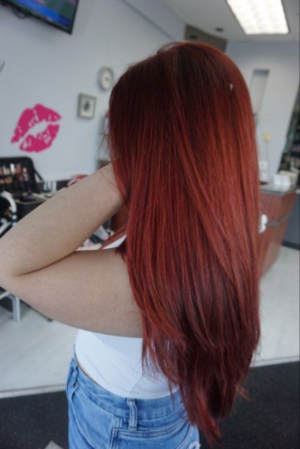 A woman with red hair is standing in front mirror