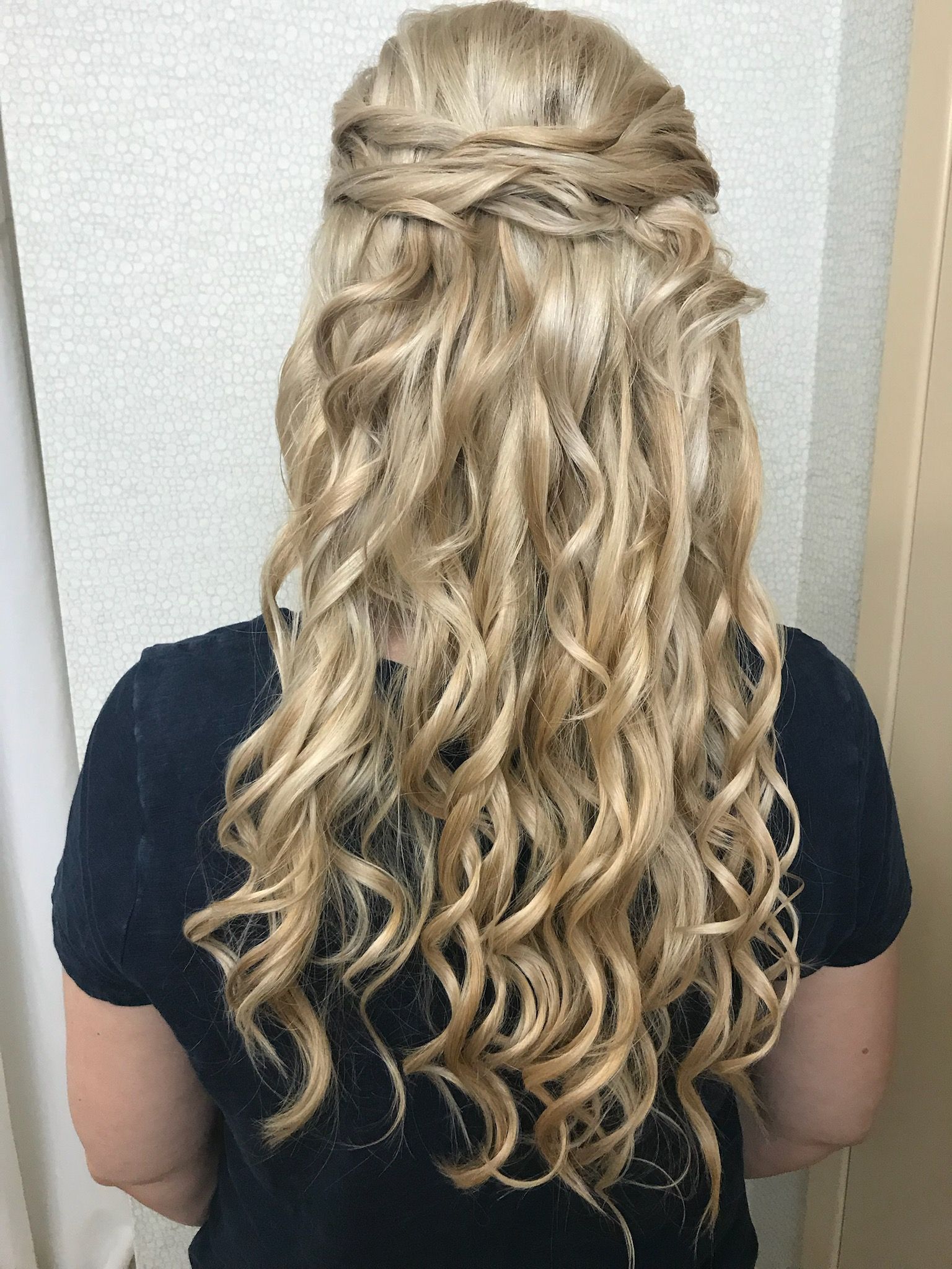 A woman with long blonde curly hair is wearing a black shirt.