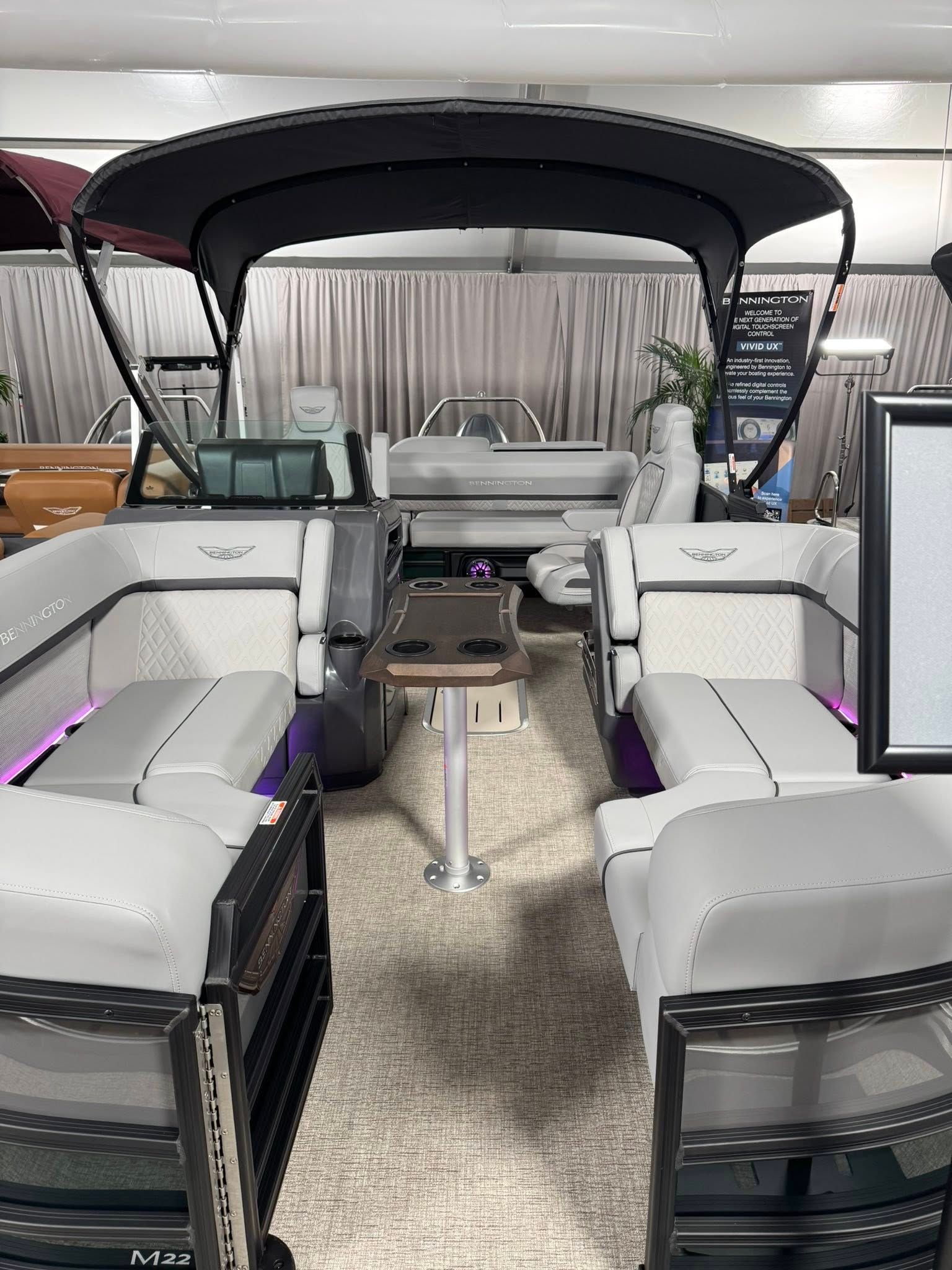 Pontoon boat interior with white seats, black canopy, and a small table.