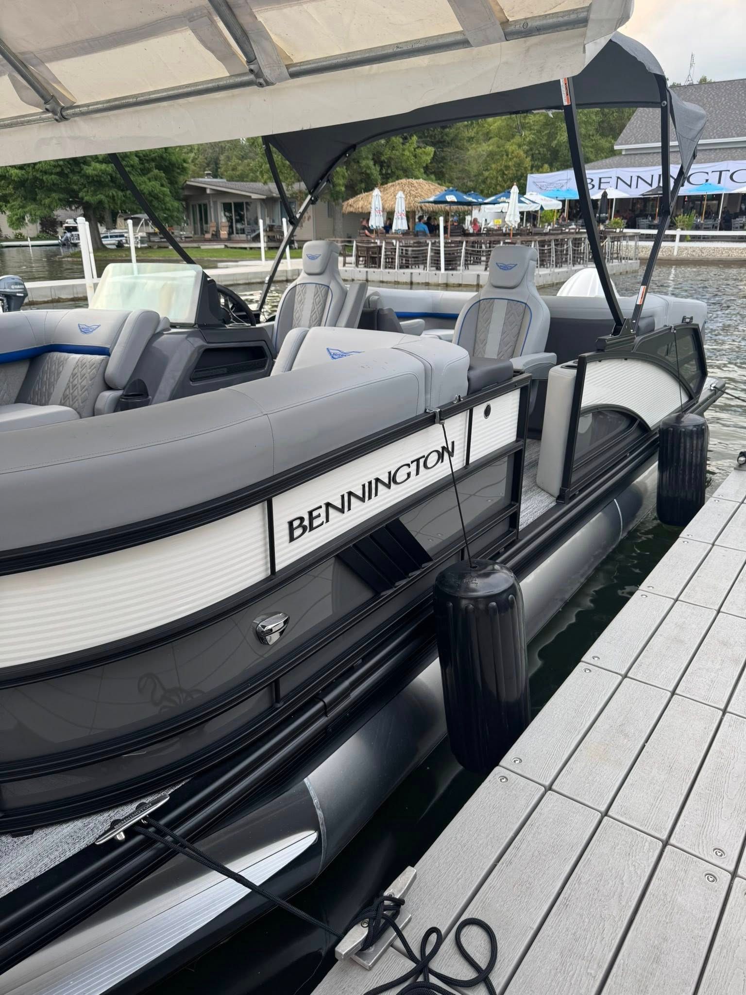 Black and gray Bennington pontoon boat docked at a wooden pier.
