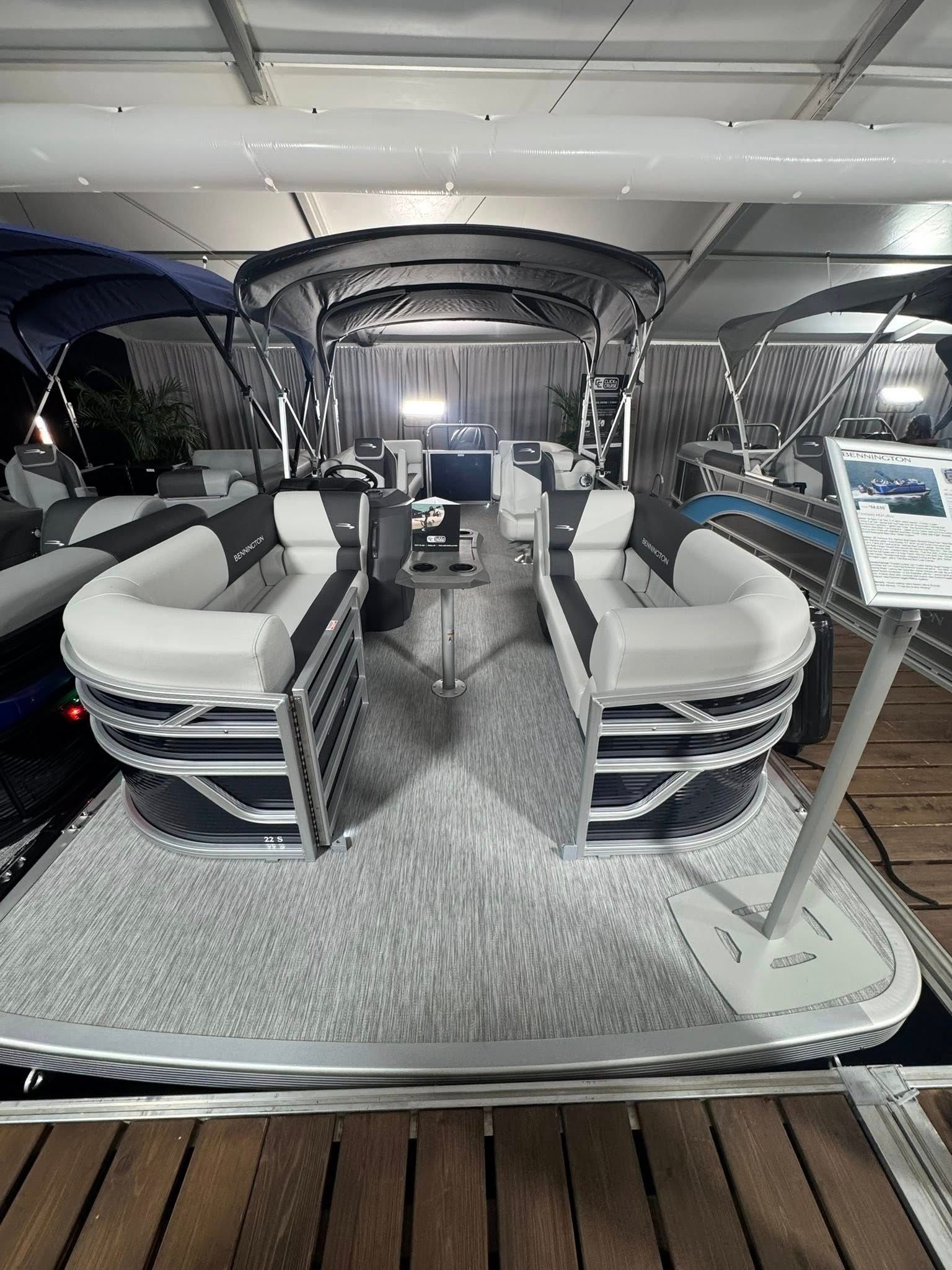 Pontoon boat with white and black seating, under a black canopy. Interior shot.