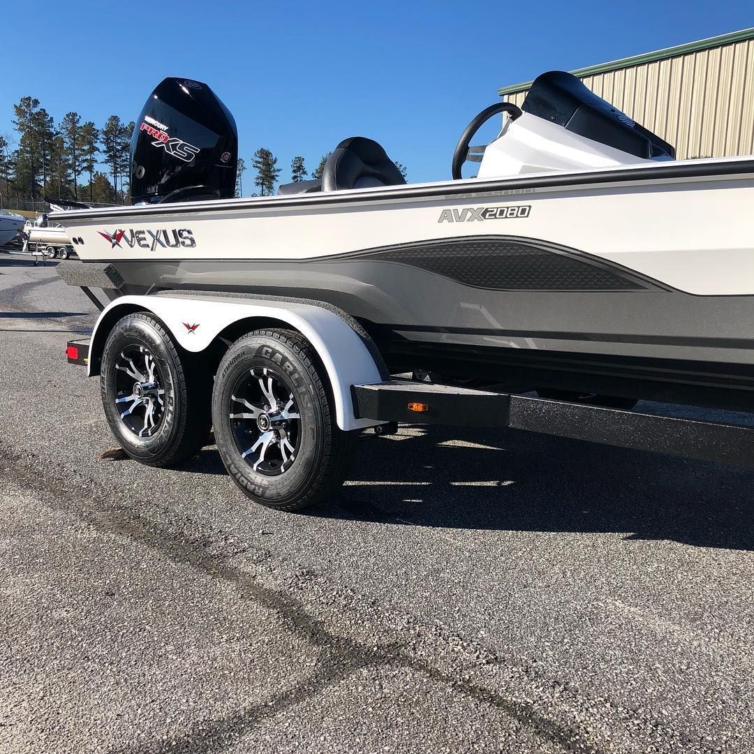White and black motorboat on a trailer with two wheels, black motor on the back.