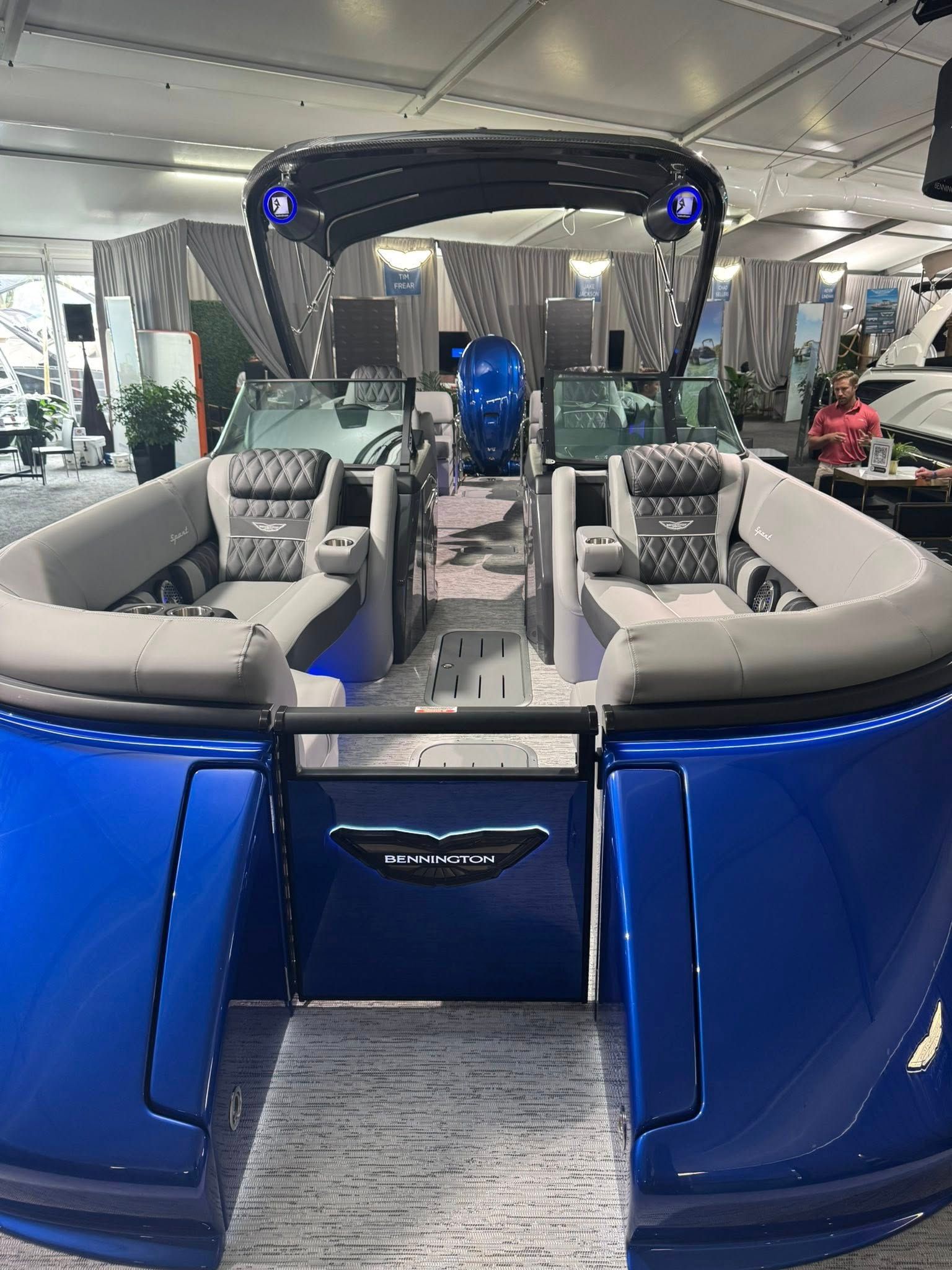 Blue pontoon boat interior with seating, console, and overhead canopy.