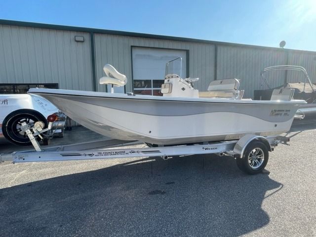 White and gray boat on a trailer, parked in front of a building.