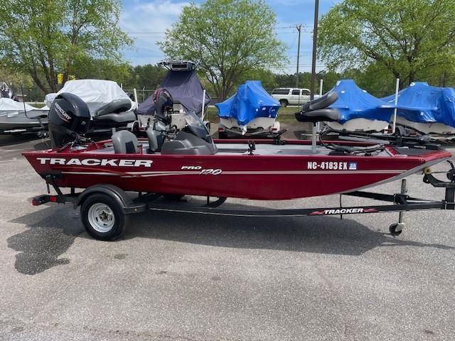 Red Tracker bass boat on trailer, parked outdoors.