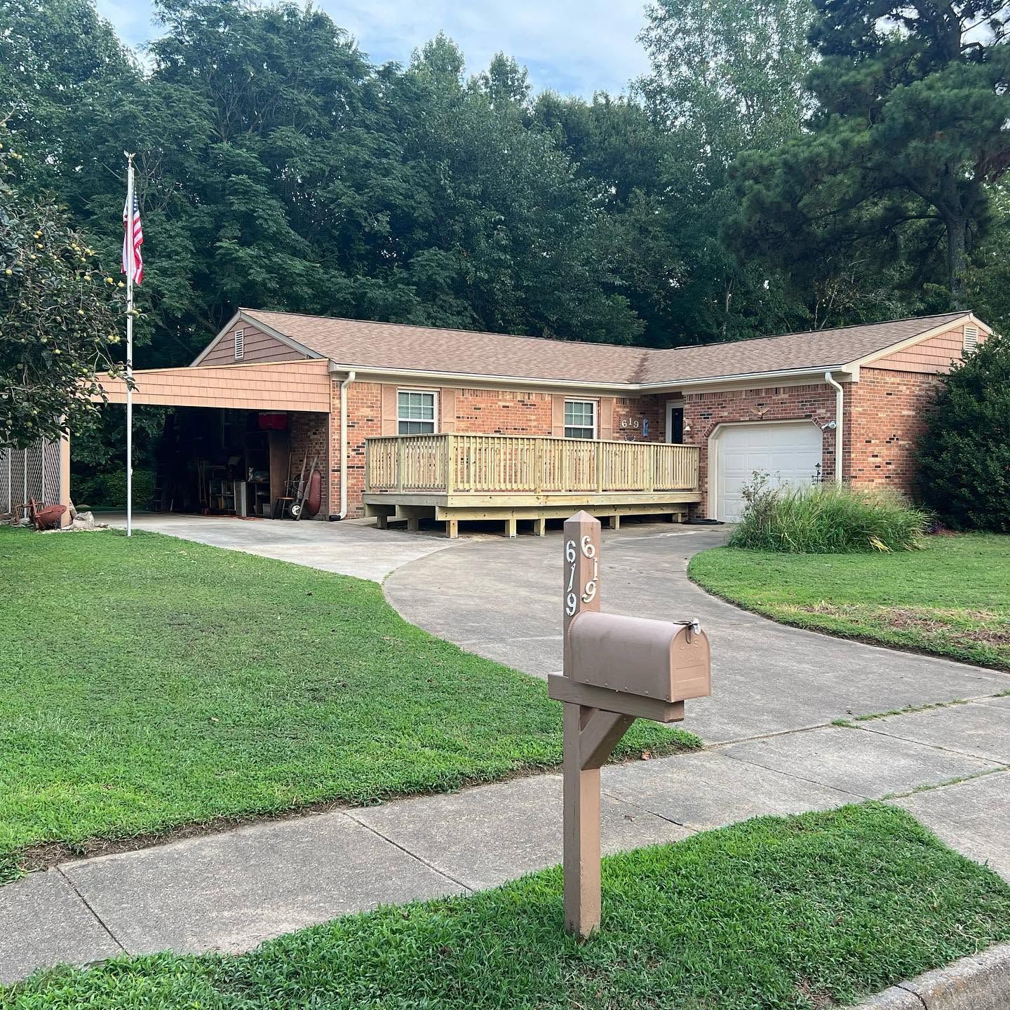 Suburban brick house with a wooden ramp, driveway, and mailbox in front