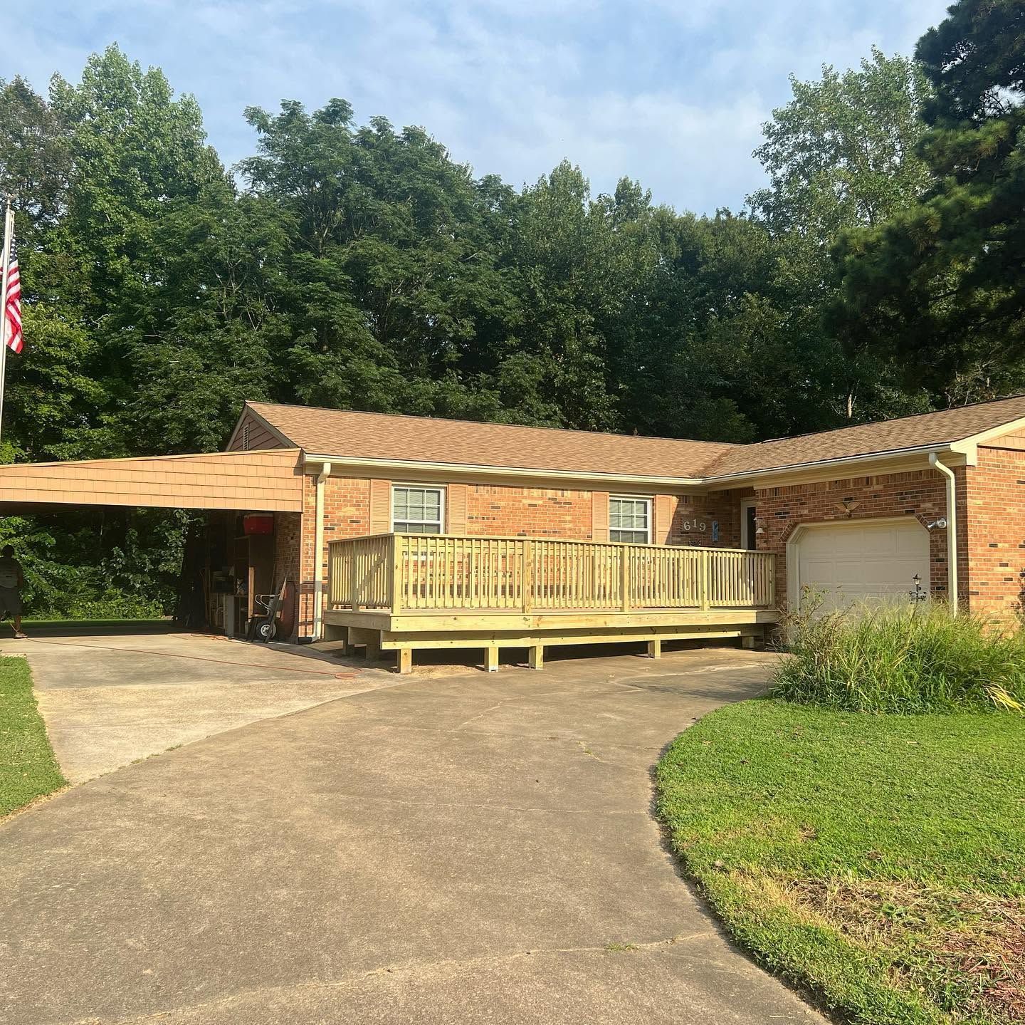 Single-story brick house with a front porch, garage, and curved driveway under a sunny sky