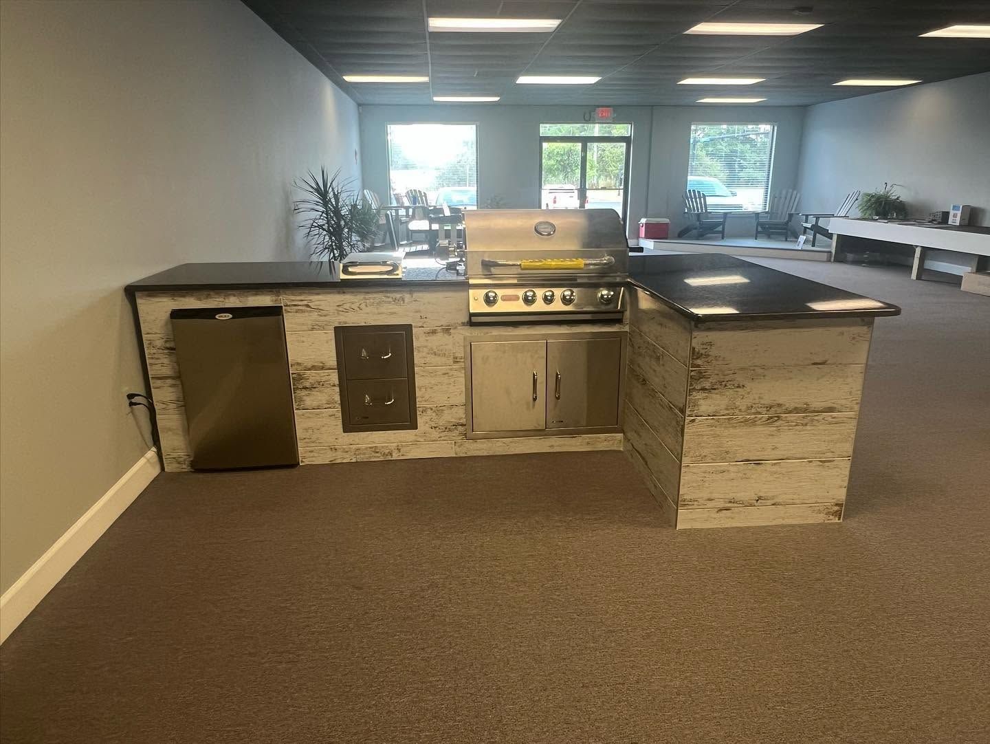 Outdoor stone grill and countertop setup under a covered patio with a carpeted floor.