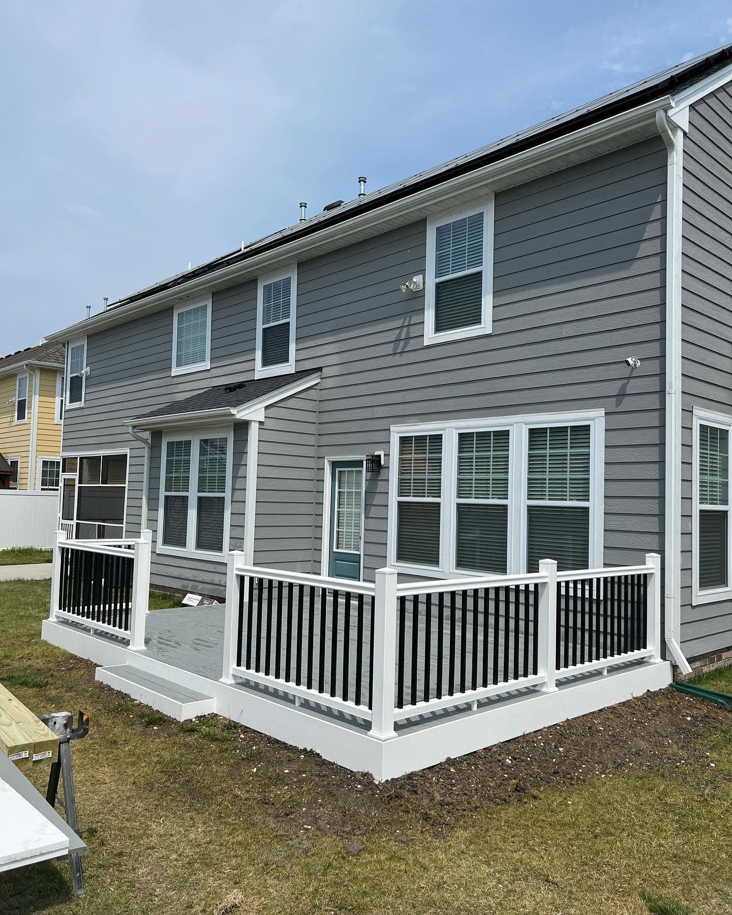 Gray two-story house with white trim and a small fenced porch and patio.