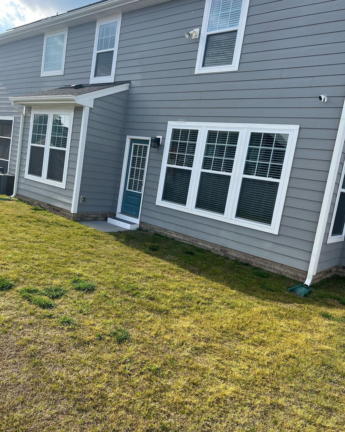 Gray two-story house with white trim and large windows, viewed from the lawn