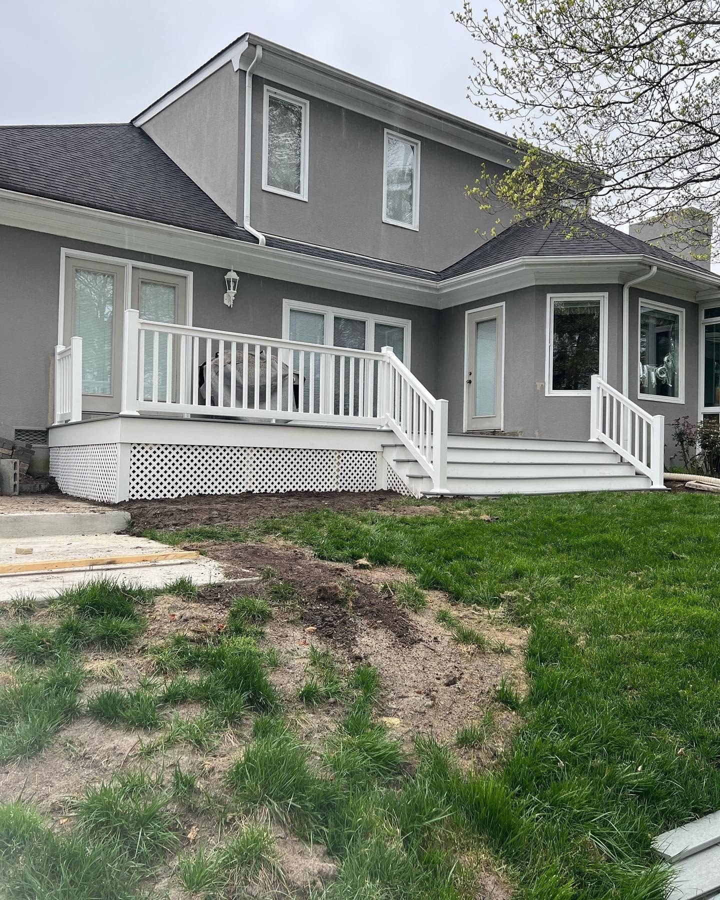 Gray house with white trim and front porch, seen from a yard with patchy grass.