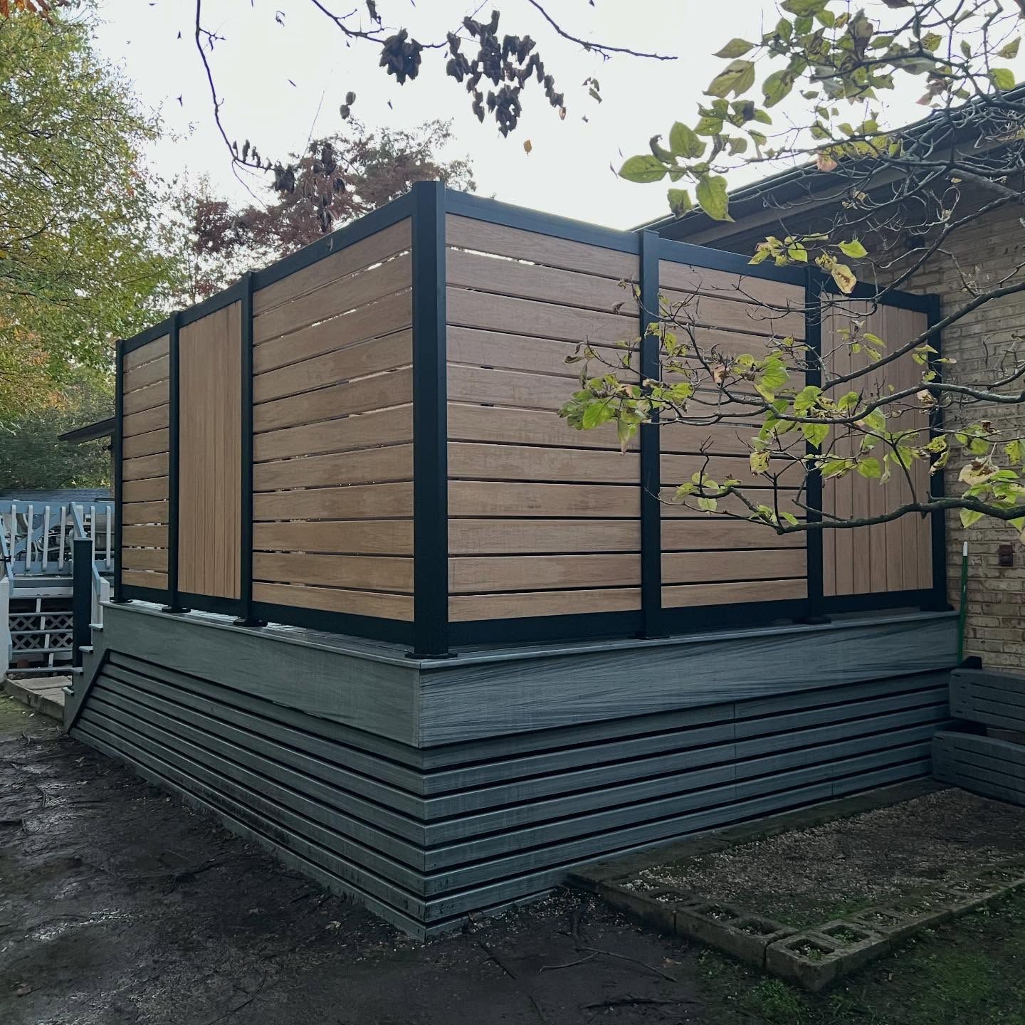 Modern wooden deck enclosure with horizontal slats on a raised gray base outdoors