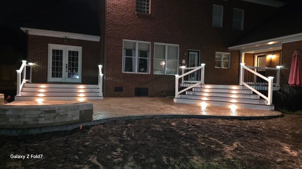 Lit brick house exterior with illuminated front steps, porch railings, and double doors at night