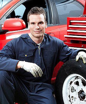 Smiling mechanic holding a tire