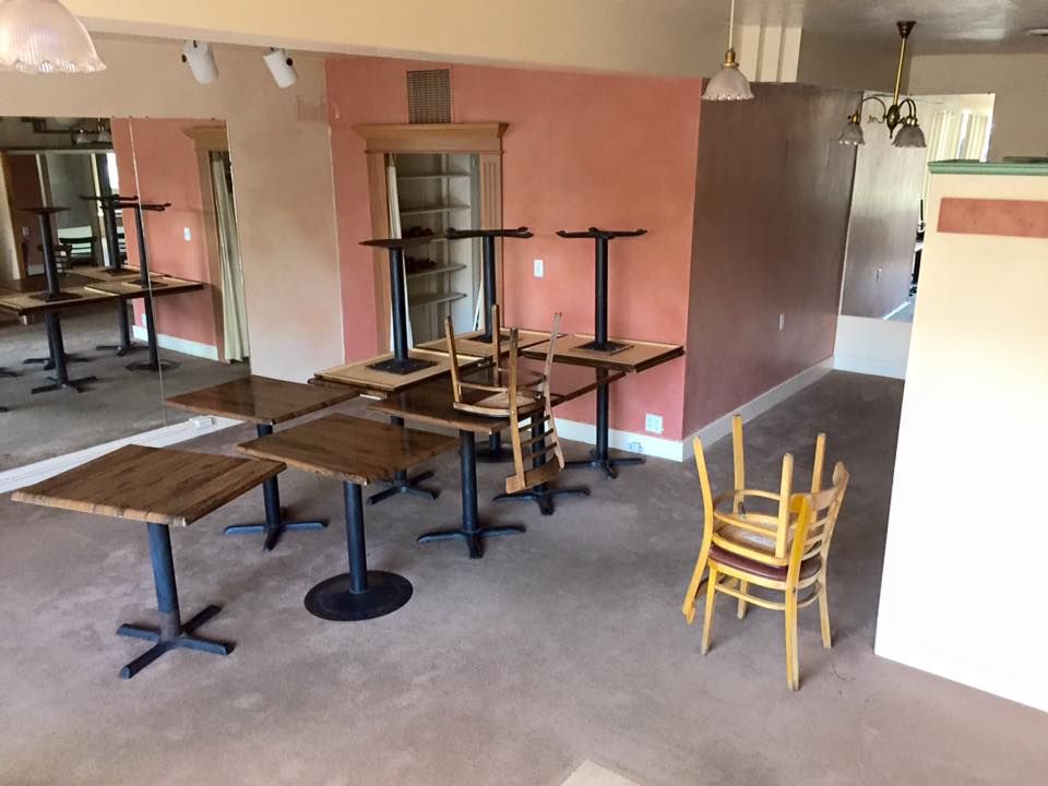 Empty restaurant interior with tables, chairs stacked, and mirrors.