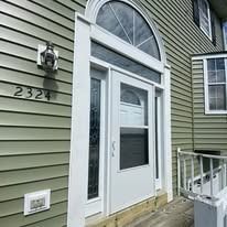 Front entrance of a house with white door frame, arched window, and address 2324.