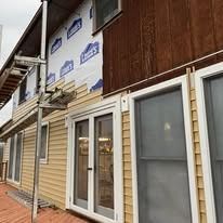 Exterior of a house with siding and windows, some areas show construction and repair.