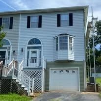 Two-story house with light blue siding, white trim, and a white garage door. Scaffold is visible.