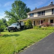 White dump truck parked on grass in front of a house on a sunny day.
