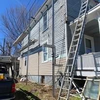 Exterior of a building with scaffolding, ladder, and siding repair in progress.